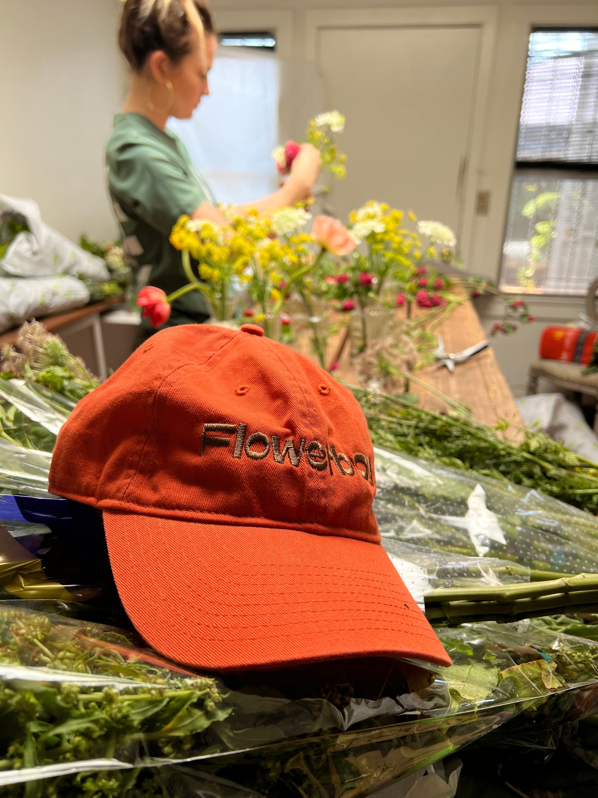 Flowerboy Project Dad Cap in Orange sitting on flowers