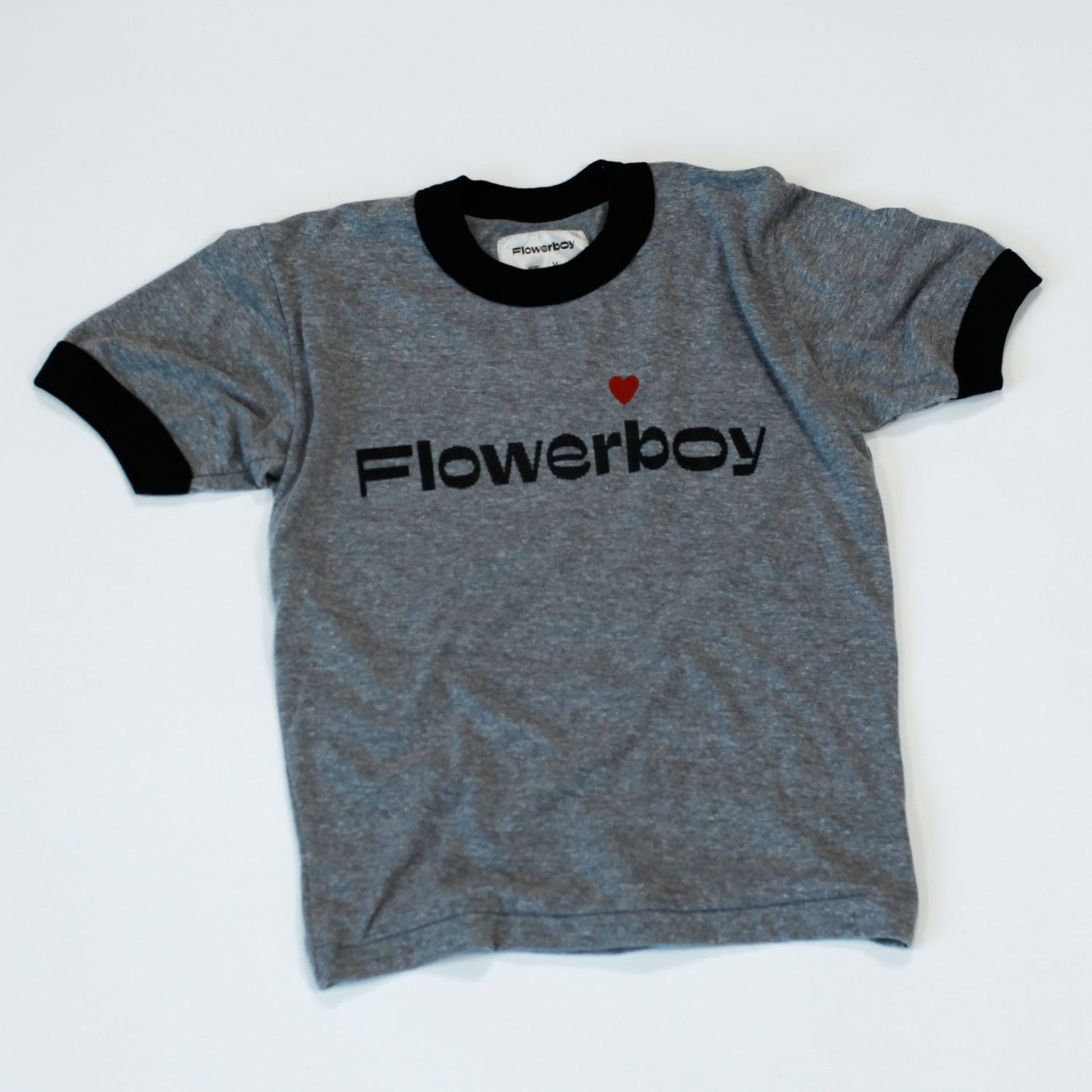 The front of our Flowerboy short sleeve baseball Tee with our digital or pixelated Flowerboy Logo with a red heart printed on the chest. The tee is grey with a black collar and black arm sleeves.  