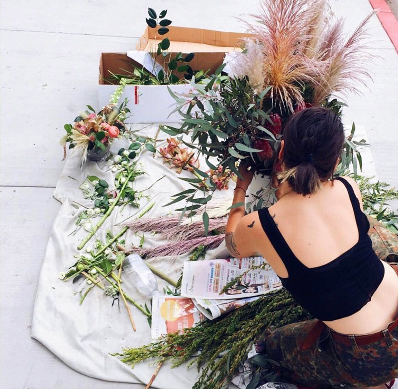 Woman arranging flowers on tarp on sidewalk